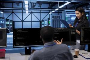 Engineer in server farm checking recovery plan, monitoring data center energy consumption. Employee in server room making sure sensors are functioning optimally, doing routine disk checks photo