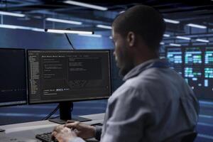 Software developer reconfiguring server farm to optimize it for data processing requirements of customers. African american man ensuring data center equipment operates efficiently photo