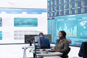Chief executive officer reviews data shown on big display in the office, screens with infographics, finance analysis and organizational progress. Telecommunications system control room. photo