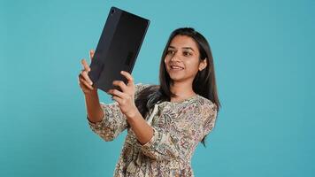 Indian narcissistic woman using tablet to take selfies from all angles. Vain social media user taking photos using digital device selfie camera, smiling happily, studio background, camera A
