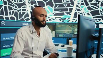 Middle eastern call center operator gives directions to the courier, avoid traffic by monitoring radar CCTV surveillance and a satellite city map. Employee helps with express delivery. Camera B. photo