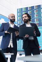 Diverse group of business specialists solve their daily tasks in control room with big screen, analyzing data numbers to ensure organizational progress. Startup management team. photo