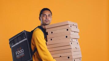 Indian delivery worker offering takeaway order to customer paying with debit card. Client buying meal from courier, swiping card on POS device, studio background, camera B photo