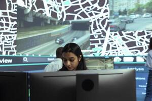 Indian woman locating delivery trucks in traffic via satellite map with gps coordinates, monitoring route and destination to ensure order shipment. Agency employee uses public surveillance system. photo