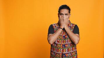 Anxious indian man covering face with palms, worried about future, isolated over studio background. Tense person massaging temples, bothered by troubling news, feeling distressed, camera B photo