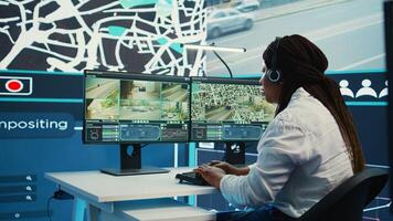African american employee tracking orders on satellite navigation with gps coordinates, looking for routes to help couriers with express shipping service. Agency worker in control center. Camera B. photo