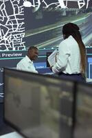 African american team studies order tracking logistics and gps coordinates of the delivery location, using CCTV surveillance footage and satellite navigation in agency headquarters. photo