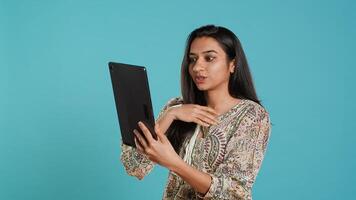 Upbeat woman having friendly conversations during teleconference meeting using tablet, studio background. Person having fun catching up with mates during online videocall on digital device, camera A photo