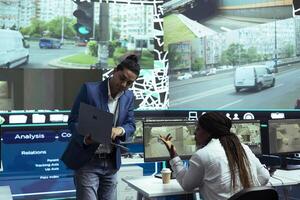 Indian manager instructing his staff in using CCTV public system to follow couriers and help with directions. Agency working on express delivery service, provide gps coordinates for order tracking. photo