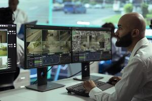 Middle eastern employee monitoring traffic surveillance footage on displays, using radar and CCTV system in observation room. Expert handling license plate recognition on security cameras. photo