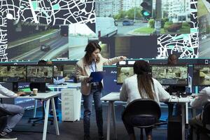 Diverse employees studying order tracking and shipment logistics to help couriers with fast delivery through city traffic. Agency utilizing CCTV system, footage and gps coordinates, pin on map. photo