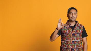 Indian man doing ok hand sign, feeling pleased, agreeing with satisfactory conclusion. Optimistic person doing okay symbol gesturing, offering positive feedback, studio background, camera A photo