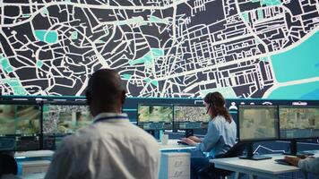 Diverse team guiding shipment cars through the city via satellite map, using gps navigation to avoid traffic for express delivery service. Agency employees operators communicating routes. Camera B. photo