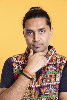 Portrait of pensive man deep in thoughts, doing reasoning hand gesturing, isolated over studio background. Close up shot of confused person doing stroking chin gesture, thinking, studio backdrop photo