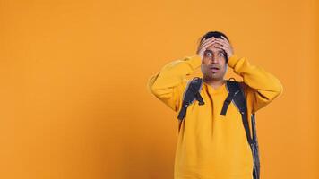 Overloaded delivery man carrying huge stack of pizza boxes, worried after making mistake. Worker encumbered by too many food orders, dropping them, feeling upset, studio background, camera B photo