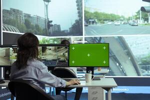 Woman employee monitoring traffic via surveillance radar footage, using a greenscreen in control center. Operator studying CCTV security system around the city streets, gathers cars information. photo
