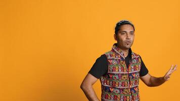 Happy indian person having fun, dancing on rhythm, enjoying leisure time. Cheerful man entertaining himself doing funky movements, isolated over studio background, camera A photo