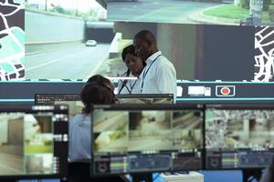 African american team leaders inspecting delivery trucks activity in traffic, ensuring easy order shipment with satellite navigation through radar system. Analyzing CCTV surveillance footage. photo