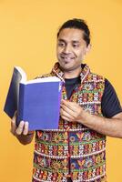 Joyous man delighted to read book, having fun and enjoying plot, isolated over studio background. Happy person excited about novel, enjoying leisure time, appreciating literature photo