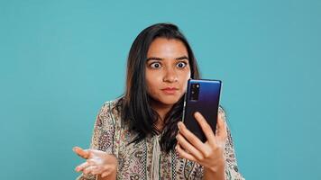 Irked woman fighting with friends during smartphone videocall, isolated over studio background. Outraged person arguing with mates during conversation on mobile phone, camera B photo