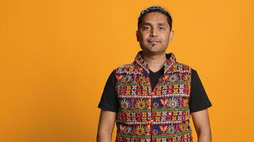 Portrait of jolly indian man with colorful garment smiling, looking pleased, isolated over studio background. Joyous person in traditional attire feeling carefree, camera A photo