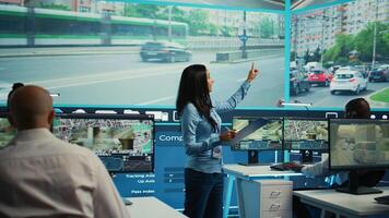 Indian supervisor assigning tasks for her operators team in observation room, people monitoring traffic through surveillance CCTV footage. Agency using satellite radar for public safety. Camera B. photo