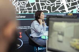 Call center operator puts headphones on to handle order delays complains from customers, working to ensure faster delivery time via satellite map and CCTV system. Cargo tracing. photo