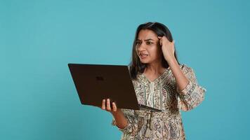 Irked woman fighting with coworkers during videocall on laptop, isolated over studio background. Outraged person arguing with colleagues during conversation on notebook, camera A photo