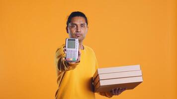 Portrait of courier isolated over studio background carrying stack of pizza boxes, close up shot. Indian employee delivering food waiting for client to answer door and pick up meal order, camera B photo