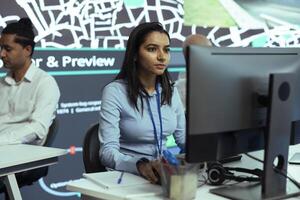 Indian female operator monitoring trucks routes and activity in traffic, working with satellite navigation and CCTV surveillance footage. Helping couriers with gps coordinates for destination. photo