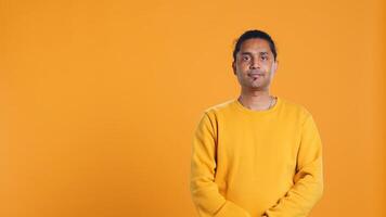 Portrait of radiant optimistic indian man with positive facial expression smiling, looking pleased. Calm merry person crossing arms, feeling satisfied, studio backdrop, camera B photo