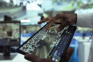 African american leader supervising delivery trucks on a tablet, monitoring shipment activity with a satellite map. Man finding gps coordinates to give directions to couriers in the field. Close up. photo
