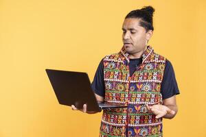 Indian man confused after seeing error message on laptop screen while doing job tasks for company, isolated over studio background. Worker perplexed by mail received on notebook photo