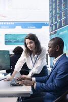 Enterprise colleagues reviewing project updates and details in monitoring room, establishing budget and other resources to achieve strategic business goals. Multiple corporation operations. photo