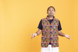 Portrait of perplexed man shrugging shoulders, hesitant to provide answer. Confused person doing questioning hand gesture, showing lack of knowledge, feeling indecisive, studio backdrop photo