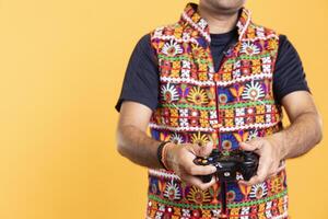 Close up shot of man wearing colorful vest playing videogames using controller, studio background. Gamer holding gamepad, participating in online multiplayer game using console system photo