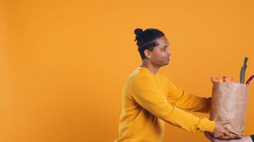 Friendly upbeat pizza delivery employee giving takeaway order to client paying with credit card. Asian man offering groceries order and digital payment method to customer, studio background, camera B photo