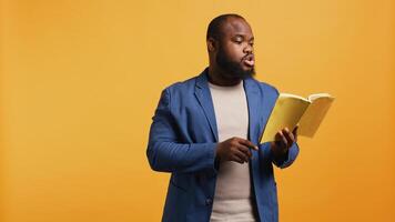 Man reading book aloud, narrating story for audience. Person enjoying literature novel, reciting from pages, entertaining spectators, isolated over studio background, camera B photo