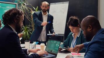 Team of associates working on resource allocation plans during a meeting, making important budgeting and staffing decisions to corelate with company objectives. Employees review strategies. Camera B. photo