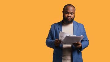 Accountant doing profit analysis for company, feeling perplexed by confusing data, studio background. Worker doing financial budgeting, scratching head, puzzled by financial figures, camera B photo