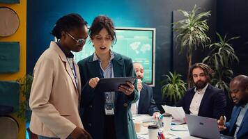 Team of business analysts reviews feedback on previous projects to work for future improvements, studying digital marketing strategies in coworking space meeting room. Startup enterprise. Camera B. photo