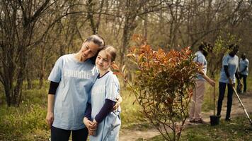 Portrait of mother and daughter volunteering to clean up a forest area, showing a sense of devotion and responsibility for the natural environment conservation. Ecological justice. Camera B. photo
