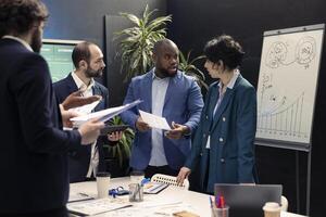 Enterprise workmates looking into project updates and details in meeting room, establishing allocate resources and tasks to achieve strategic business goals, corporation operations. photo