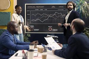 PR and marketing specialists following customer and market trends in an informative meeting, evaluating infographics together on interactive board. Business associates discussing enterprise growth. photo