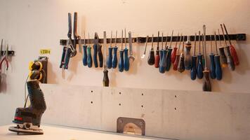 Chisels, screwdrivers, wrench and pliers on wall in carpentry studio, panning shot. Close up of various woodworking tools on rack in workshop used for repairing or creating wooden objects photo