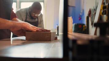 Man putting lumber block through spindle moulder, creating smooth edges on wooden piece. Joiner using heavy machinery to craft joints for furniture and structures, camera B close up photo