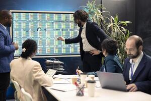 Corporate employees meeting in a conference room to discuss project updates, gathering important information from reports and planning steps to coordinate with business goals. Employee engagement. photo