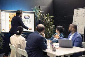 Team of business employees examining statistics and infographics on interactive board, joining forces together to gather insight for development. Coworkers discussing legal changes. photo