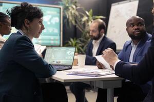 Team of business associates debating ways to increase profit in a decisional conference, analyzing sales info to conclude project. Enterprise colleagues joining forces to accomplish objectives. photo