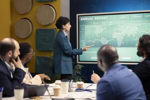 Marketing specialist showing infographics in a status update meeting, studying customer satisfaction and retention with annual data reports. Employee operating interactive board. photo